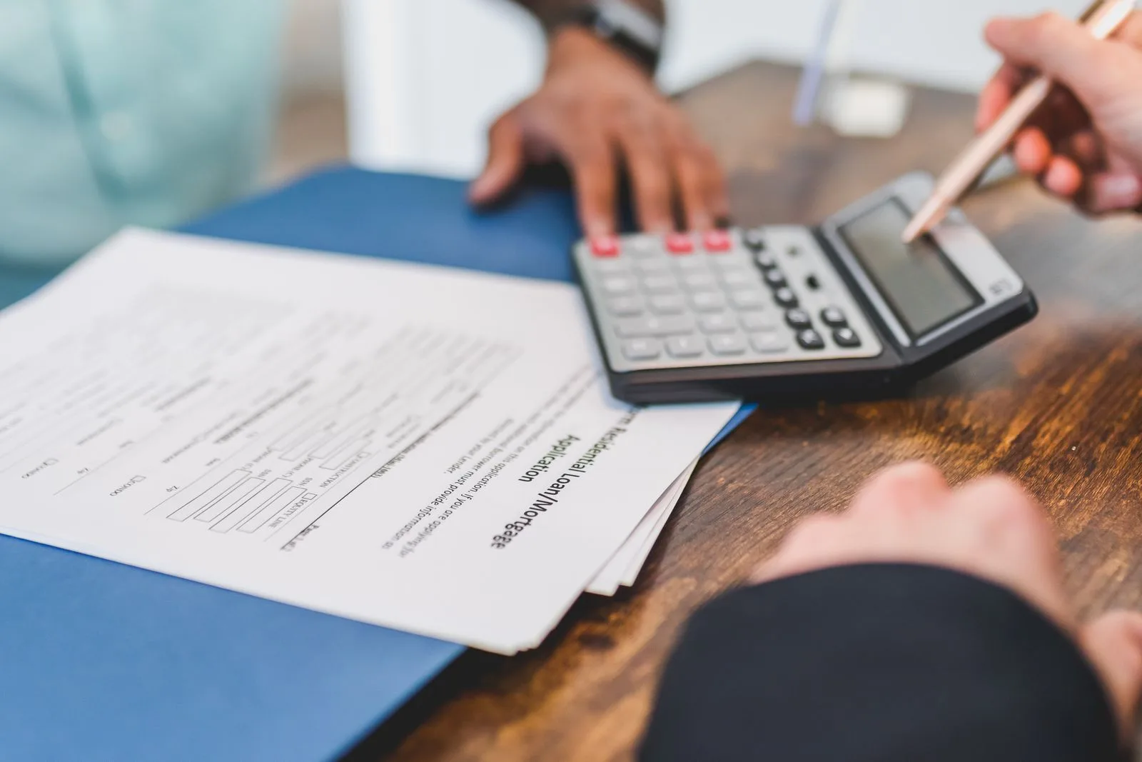 Hände bei einer Finanzierungsberechnung mit Rechner und Unterlagen
