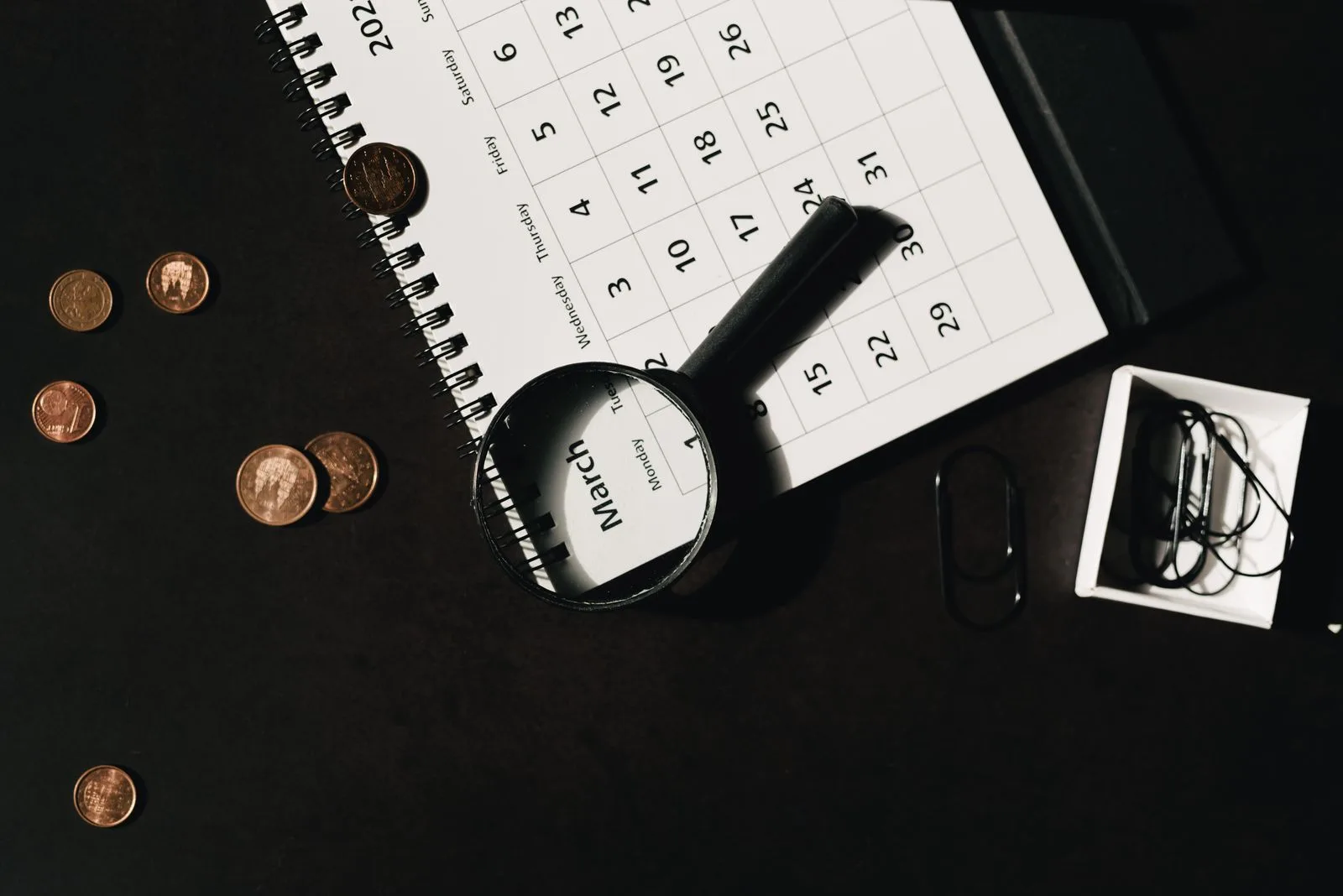 Kalender, Lupe und Münzen als Symbol für vorausschauende Finanzplanung